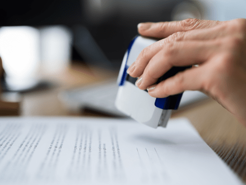 hand van vrouw die stempel boven papieren houdt